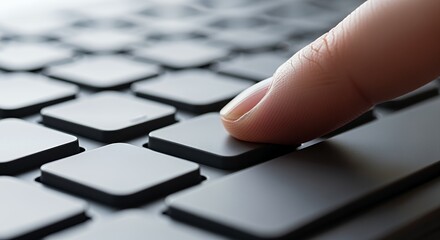 A finger gently presses a key on a sleek, modern keyboard, showcasing the precise action of typing and digital interaction.