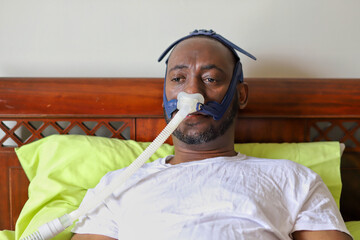 An African-American man wearing cpap mask while laying in bed
