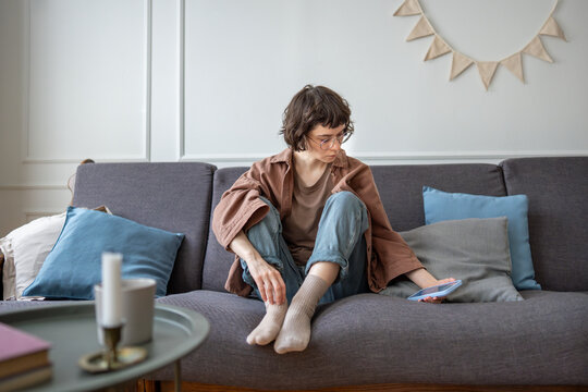 Frustrated upset woman checks phone waiting message or call feels lost, solitude at home without communication. Thoughtful unhappy girl looks on screen smartphone suffers from haters online bullying.