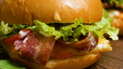 Freshly made burger showing crispy bacon, fresh lettuce, juicy tomato slices, and creamy mayonnaise between two halves of a brioche bun, resting on a wooden surface
