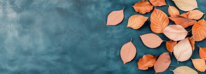 Vibrant fall leaves scattered artistically on a dark teal surface showcasing autumn colors and textures