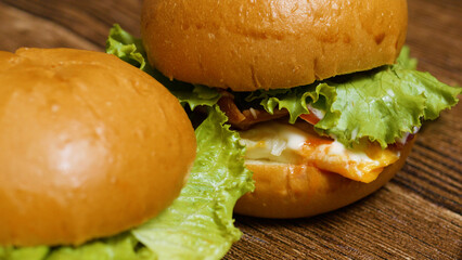 Two appetizing burgers with melted cheese, crispy bacon, fresh lettuce, and juicy tomatoes are...