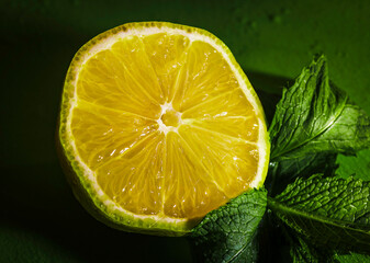 A piece of a lemon on the dark green background