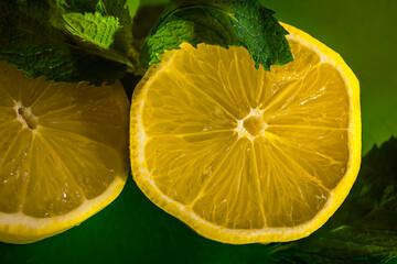 A two pieces of a lemon on the dark green background