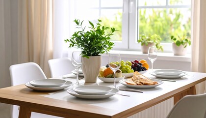 A sunlit dining table is set for a meal, featuring fresh fruit, bread, and elegant tableware near a window.