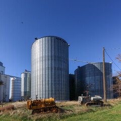 Two rusty tractors in front of grain elevators