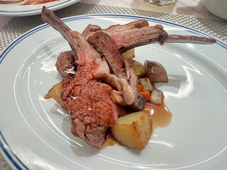Grilled lamb steak served with savory sauce and potatoes.