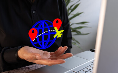 Close-up of a professional's hands using a computer with an icon 3 of a globe and an airplane, indicating air travel around the world