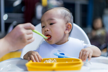 baby is eating food from a yellow plate