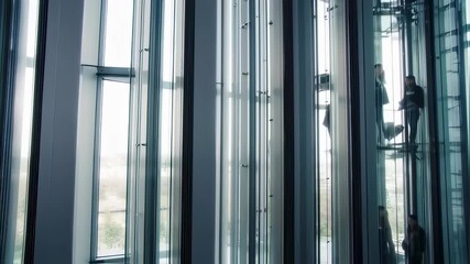 Modern office building with a glass elevator transporting people up and down - Powered by Adobe