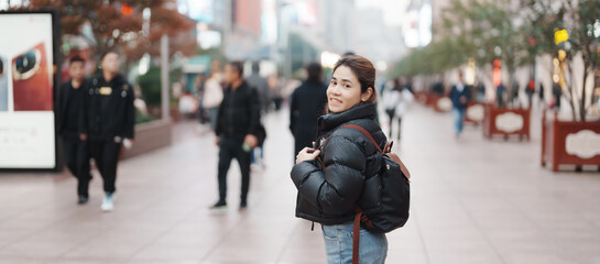 woman traveler visiting in Shanghai, China. Happy Female Tourist sightseeing in Nanjing road,...