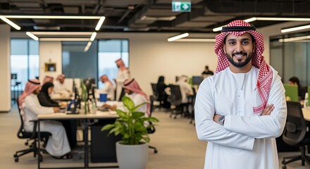 Confident Middle Eastern businessman stands with arms crossed in a modern, busy , showcasing success and leadership in a diverse workplace.