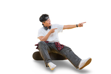A young man is sitting on a skateboard and pointing to something with both hands on png background © STOCK88PHOTOGRAPHER