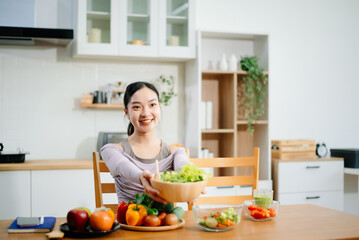 Smiling woman in a modern kitchen with fresh fruits, veggies, blender, and juice, embracing clean eating, wellness, and a healthy lifestyle