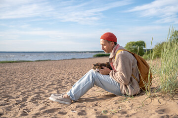 Attentive man comfort cat companion while sit on coastal shoreline. Animal travel adaptation, cat...