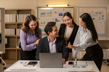 A man and three women are sitting at a table with a laptop