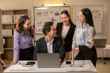 A group of people are sitting around a table with a laptop