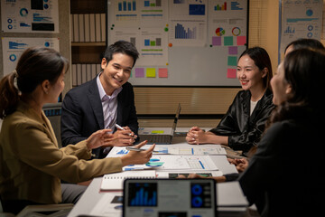 A group of people are sitting around a table with a whiteboard behind them