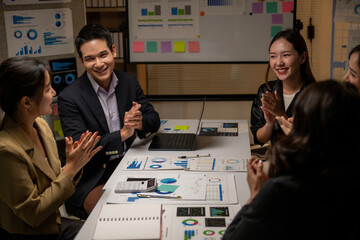 A group of people are sitting around a table with a white board behind them