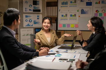 A group of people are sitting around a table with a lot of papers and graphs