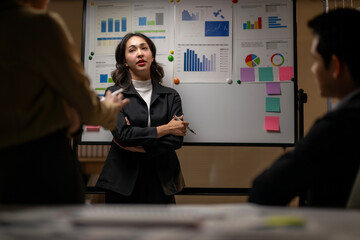 A woman standing in front of a white board with a man