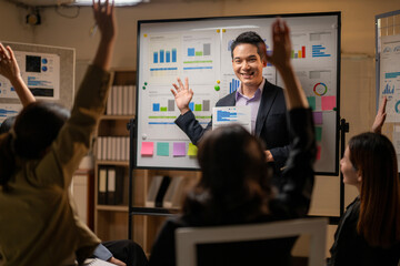 A man is standing in front of a white board with a group of people watching him