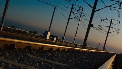 A train track stretching towards the horizon, capturing the essence of travel and transportation. The track's perspective guides the eye, under the network of powerlines.
