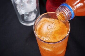Pouring  soft drink and ice in glass