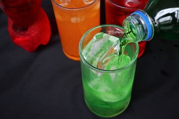 Pouring  soft drink and ice in glass