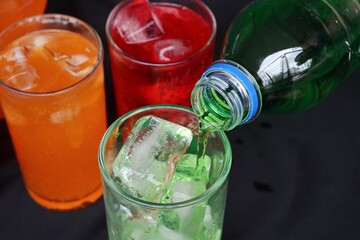 Pouring  soft drink and ice in glass