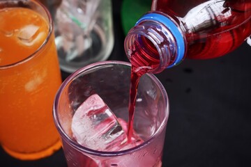 Pouring  soft drink and ice in glass