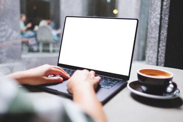 Mockup image of a woman working and typing on laptop computer with blank white desktop screen in...