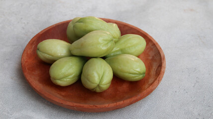 Baby chayote (labu siam) on wooden plate with grey background	