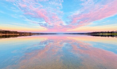 Fototapeta premium Serene Sunset Reflection Over Calm Lake Surface