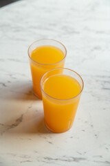 Two Glasses of Orange Juice on White Marble Table