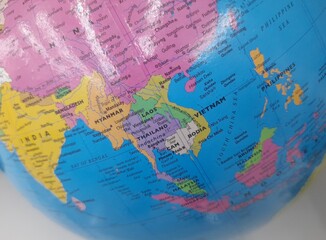 A close-up view of a colorful globe showing Southeast Asia, including countries like Thailand,...