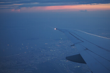 View of city lights from airplane wing during sunset