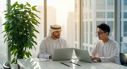 Two diverse businessmen collaborate on laptops in a modern , showcasing global teamwork and partnership.