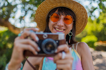 Charming woman with camera on the street. Portrait of a beautiful girl smiling on the street....
