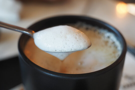 Coffee with foam served in a black mug at a cozy cafe
