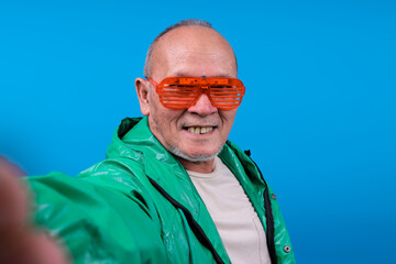 Cheerful Senior Asian Male Taking Close Up Selfie Over Blue Background