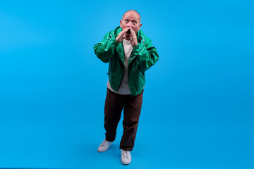 Full Body Of Elderly Asian Male With Hands Cupped Around Mouth Shouting On Blue Background