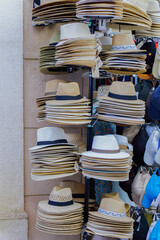 Panama hats stacked high on display at an outdoor market, offering various styles and colors for shoppers