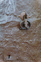 Close-up of an old weathered metal door featuring a distinctive bull-shaped handle, highlighting...