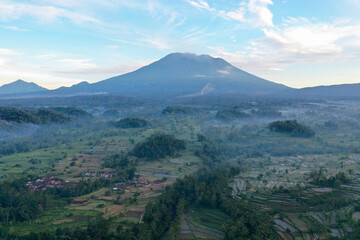 Fototapeta premium Misty Morning Over Rice Fields and Mount Agung Volcano