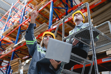Male and female industrial staff coordinating warehouse management through digital devices,...