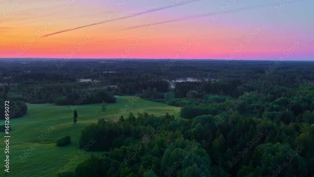 Poster drone video of forest landscape and open fields at colorful sunset with distant mist