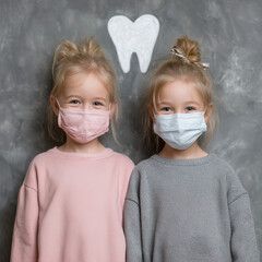 Two young girls wearing masks and standing next to a tooth sign. Scene is lighthearted and playful, as the girls are posing for a picture while wearing masks