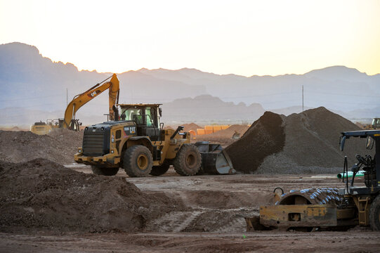 Heavy equipment moves earth at a residential development site, with loaders and excavators operating during early grading and land preparation phases of construction