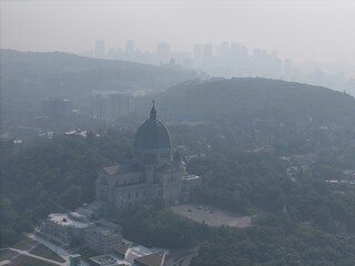 Aerial view of Saint Joseph's Oratory in Montreal under heavy smog, haze and forested hills. c.